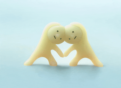 a couple of figurines with faces on them making a heart shape