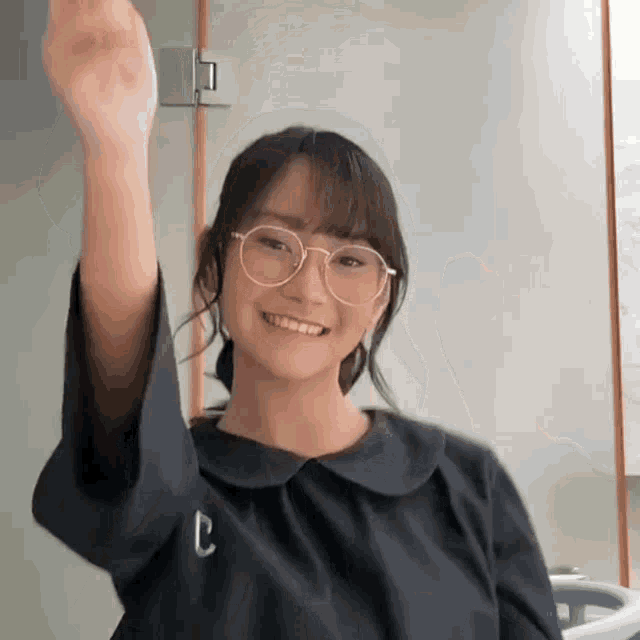 a girl wearing glasses and a black shirt has the letter c on her sleeve