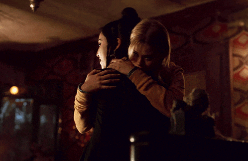 two women are hugging in a dark room
