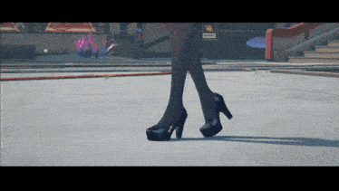 a woman wearing black high heels is walking on a concrete surface