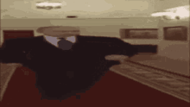 a man in a suit and tie is walking down a hallway with a red carpet .
