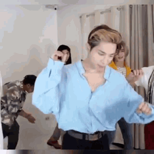 a man in a blue shirt is dancing with a group of people .