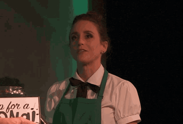 a woman in a green apron is holding a sign that says " p for a nail "