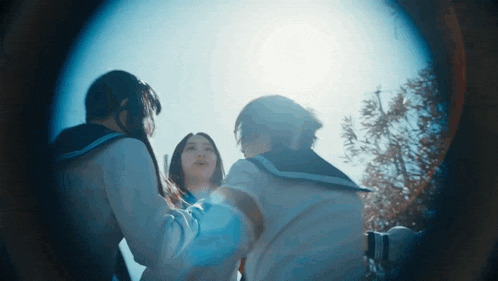 a group of girls are standing in a circle looking at the sun