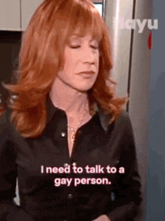 a woman with red hair is talking to a gay person in a kitchen .