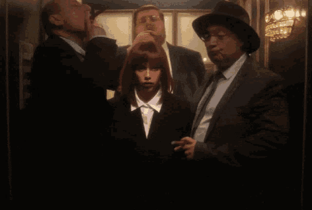 a group of people in suits and hats are standing in a dark room