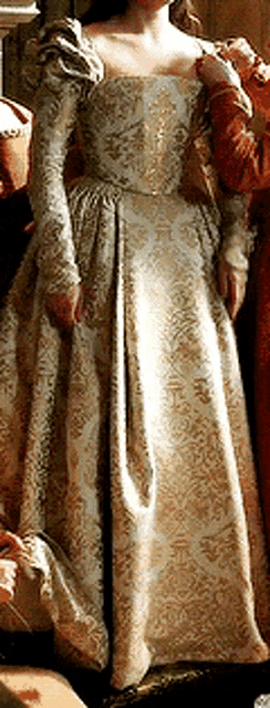 a woman in a long dress with long sleeves is standing next to two other women .
