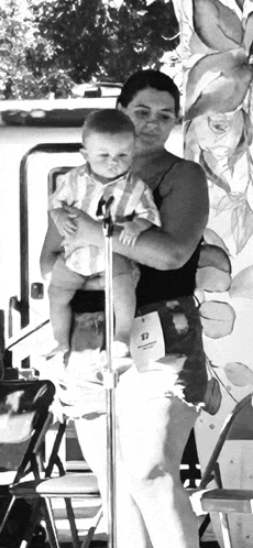 a black and white photo of a woman holding a baby in her arms .