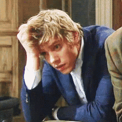 a man in a blue suit is sitting with his hand on his forehead
