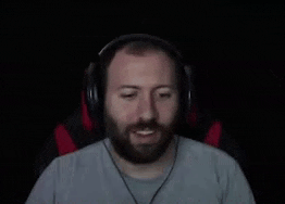 a man with a beard is wearing headphones and making a face