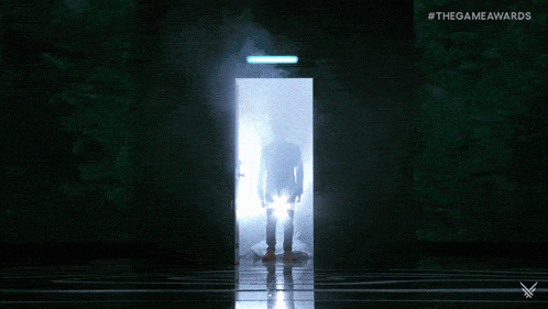 a man in a suit is standing in front of a light with #thegameawards written on it