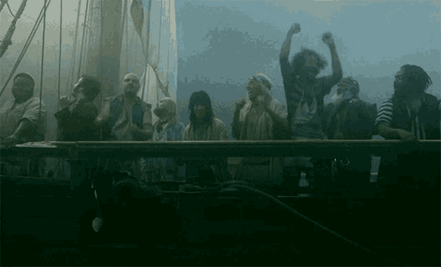 a group of people standing on a boat with their arms up