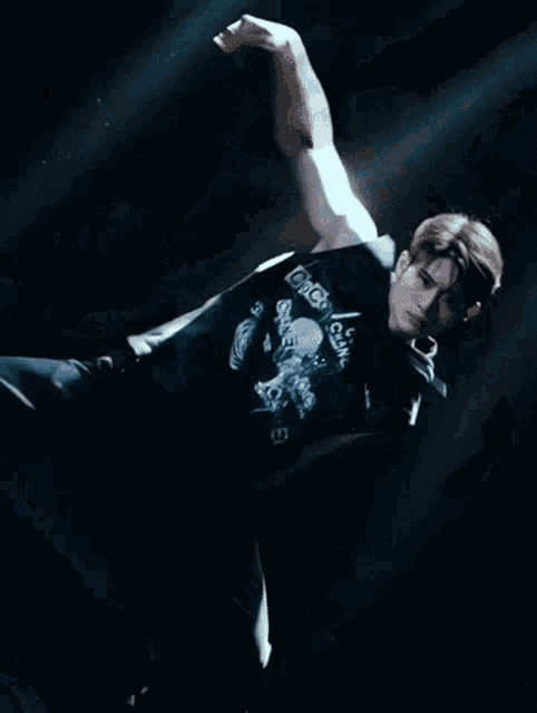 a man in a black shirt is dancing in the dark .