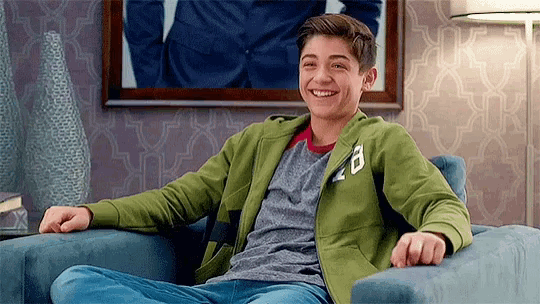 a young man is sitting in a chair smiling .