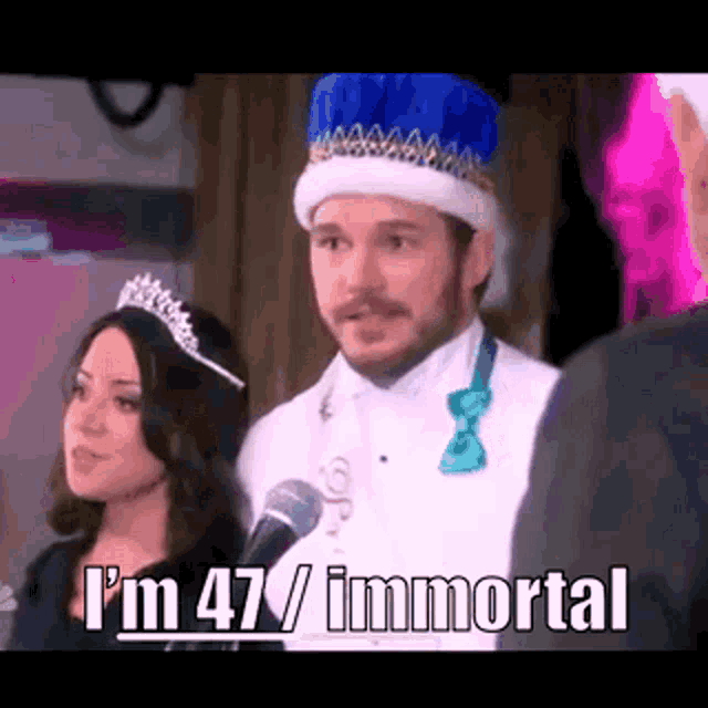 a man wearing a crown is standing next to a woman wearing a tiara and bow tie .