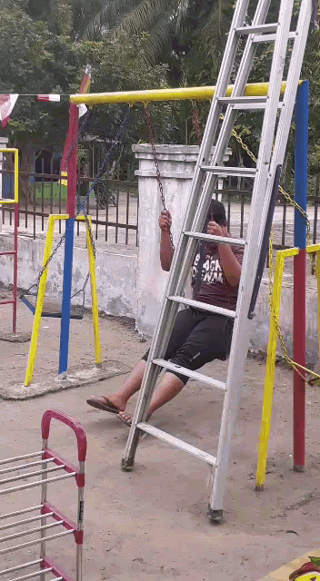a man wearing a shirt that says 4chan is sitting on a ladder