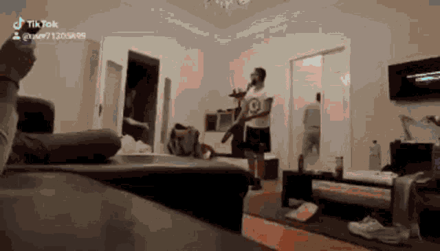 a man is standing in a living room holding a microphone while a woman sits on a couch .
