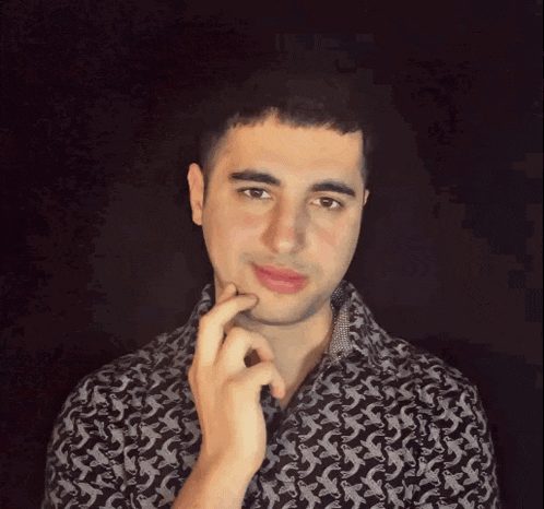 a man with his hand on his chin wearing a black and white shirt with the letter s on it