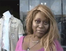 a woman wearing a pink top and a necklace with the letter t on it