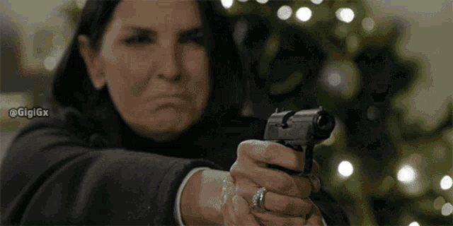 a woman with a ring on her finger is pointing a gun at the camera .
