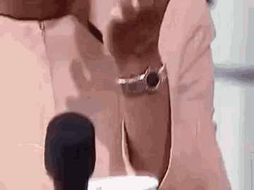 a woman in a pink suit is talking into a microphone while wearing a watch .