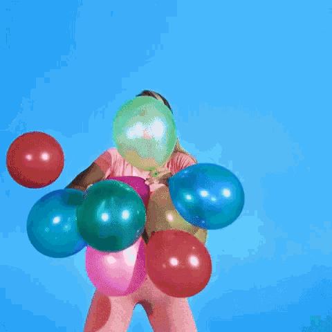 a woman is holding a bunch of colorful balloons in her hand .