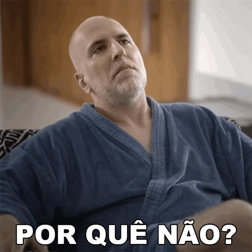 a bald man in a blue robe is sitting on a couch and says por que não