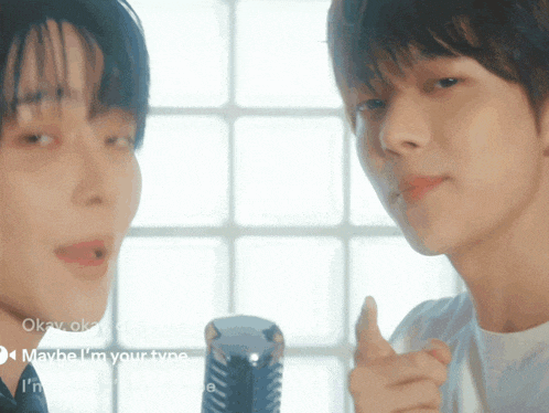 two young men are standing next to each other and one is pointing