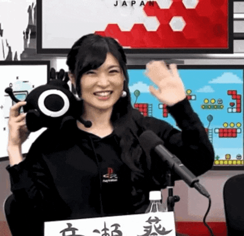 a woman holding a stuffed animal in front of a microphone with a sign that says japan on it