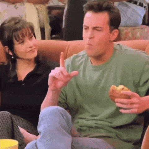 a man in a green shirt is eating a sandwich while sitting on a couch