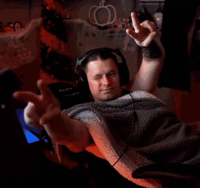 a man wearing headphones and a blanket is giving a peace sign