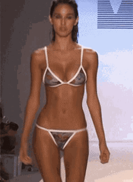 a woman in a bikini walks down a runway at a fashion show .