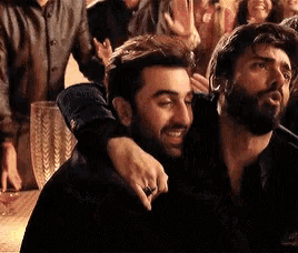 a man with a beard is hugging another man in a crowd .