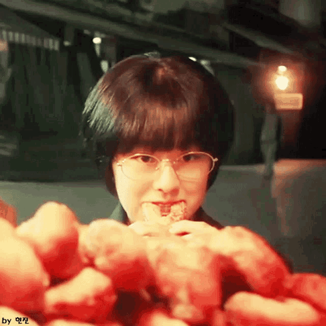a girl with glasses is eating a piece of food
