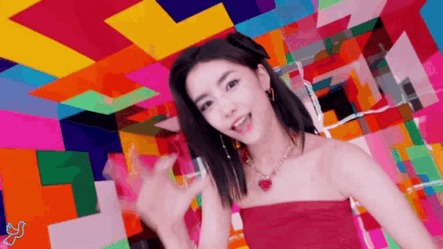 a woman in a red dress and necklace is dancing in front of a colorful background .