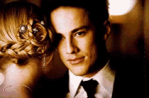 a man in a suit and tie is standing next to a woman in a braided bun