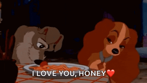 a couple of cartoon dogs are sitting at a table with a plate of spaghetti and a tomato .