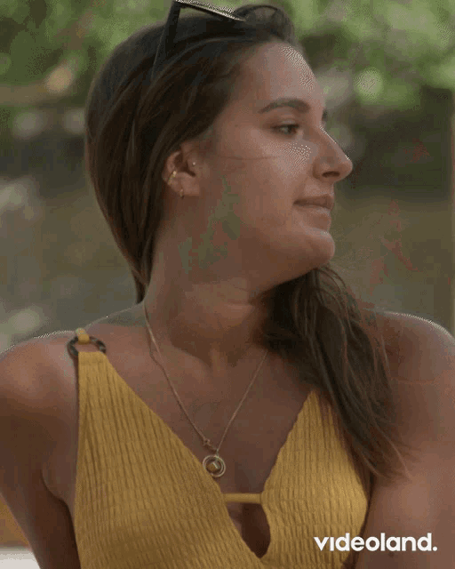 a woman wearing sunglasses and a yellow top is laughing with videoland written on the bottom