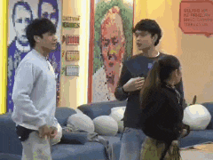 a group of people are standing in front of a painting of a man 's face ..