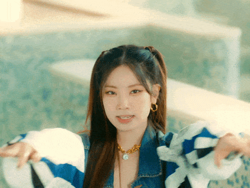a woman wearing a blue and white striped jacket and a necklace with the letter g on it