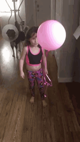a little girl is holding a pink balloon in her hand