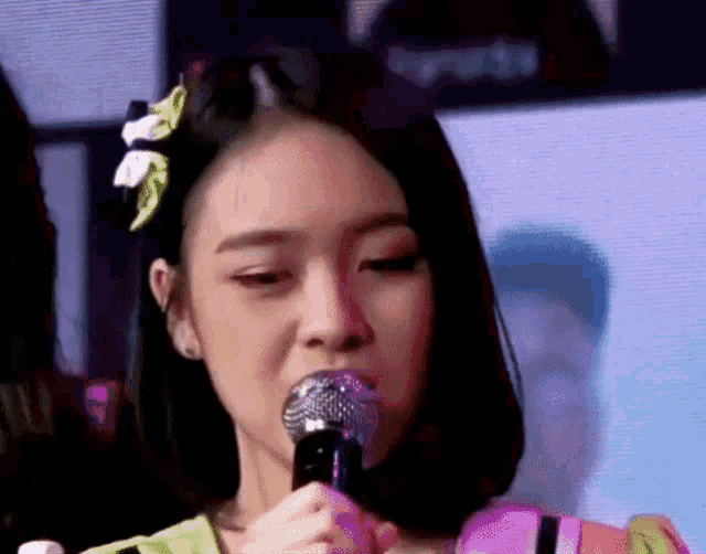 a girl with a flower in her hair is holding a microphone