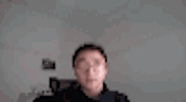 a blurry picture of a man wearing glasses and a jacket .