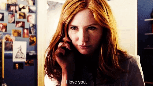 a woman with red hair is talking on a cell phone and says " i love you "