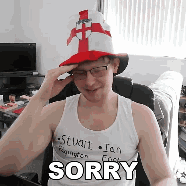 a man wearing a hat and a tank top with the word sorry on it
