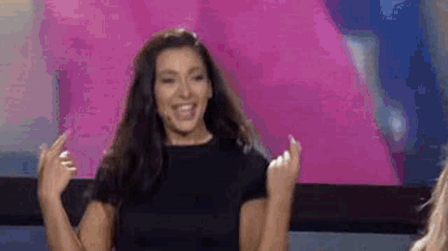 a woman is standing on a stage with her arms in the air and smiling .