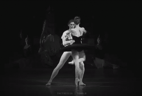 a black and white photo of two ballerinas dancing on a stage .