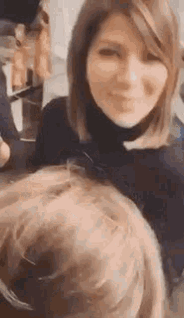 a woman in a black turtleneck is smiling and looking at the camera while holding a child 's head .