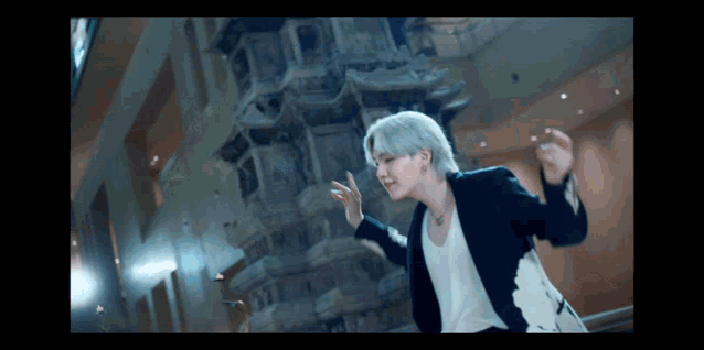 a man in a black jacket is dancing in front of a large building