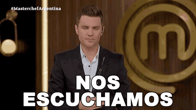 a man in a suit stands in front of a masterchef logo and says nos escuchamos